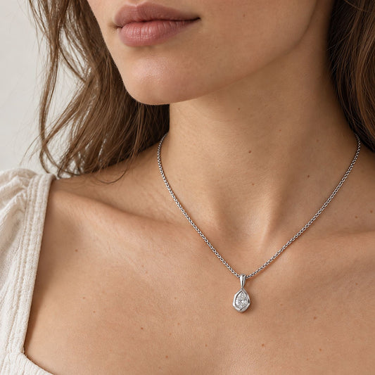Woman in a cream square-neck top wearing a silver tone stainless steel teardrop pendant necklace at the collarbone