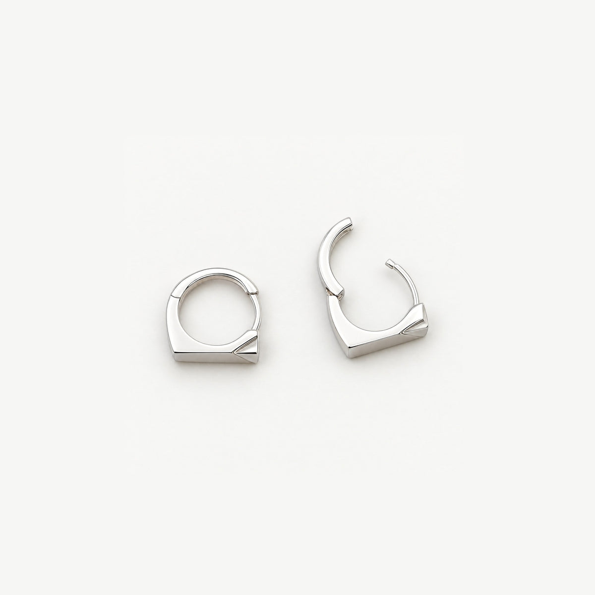 Two sterling silver rectangle huggie earrings from above, one open on its hinge to show the snap closure and inner band