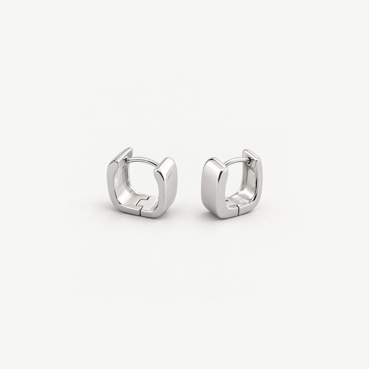 Small square sterling silver huggies standing side by side, the clicker wire and polished inner band of one in view
