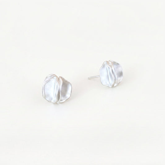 Pair of sterling silver statement stud earrings with folded petal detail on a plain near-white background