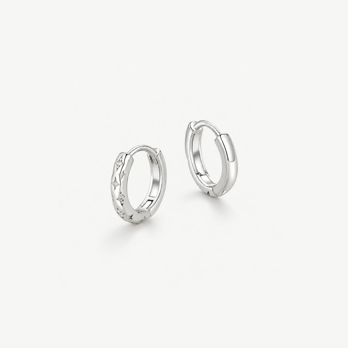 Pair of sterling silver star huggie hoop earrings with engraved four point stars and small CZ accents