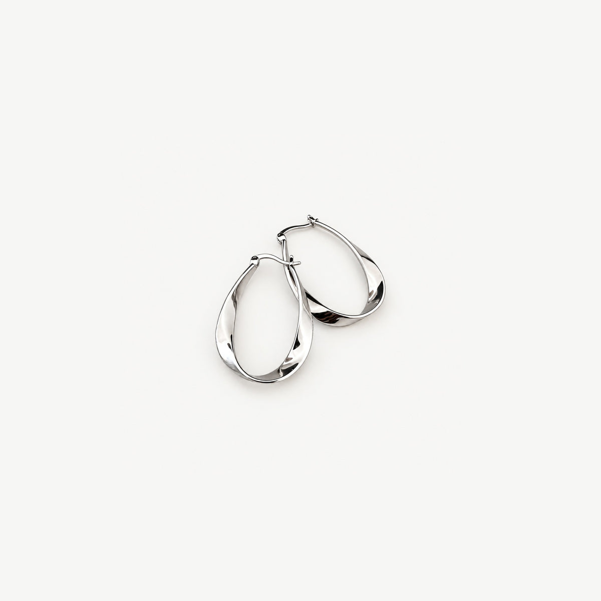 Two sterling silver twisted hoop earrings overlapping at an angle, showing the ribbon twist and the hinged latch wire