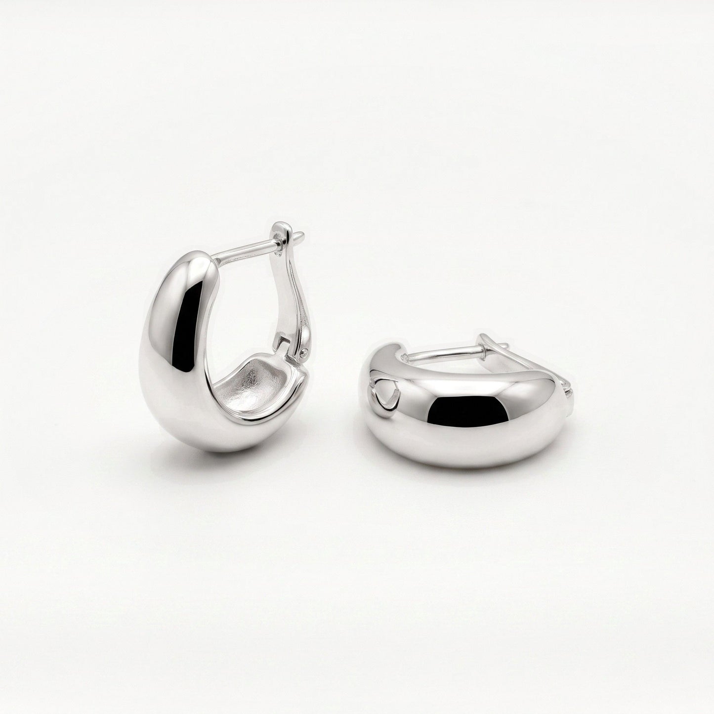 Pair of sterling silver U shaped huggie hoop earrings, one tilted to show the lever back closure