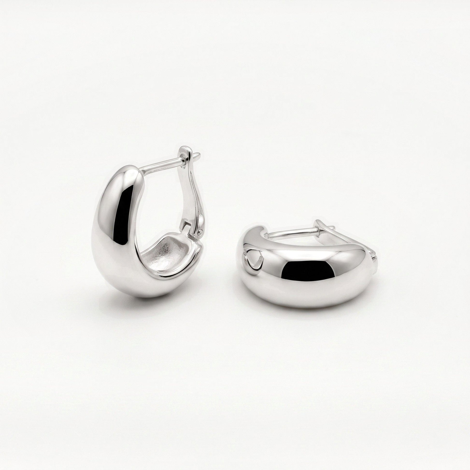 Pair of sterling silver U shaped huggie hoop earrings, one tilted to show the lever back closure