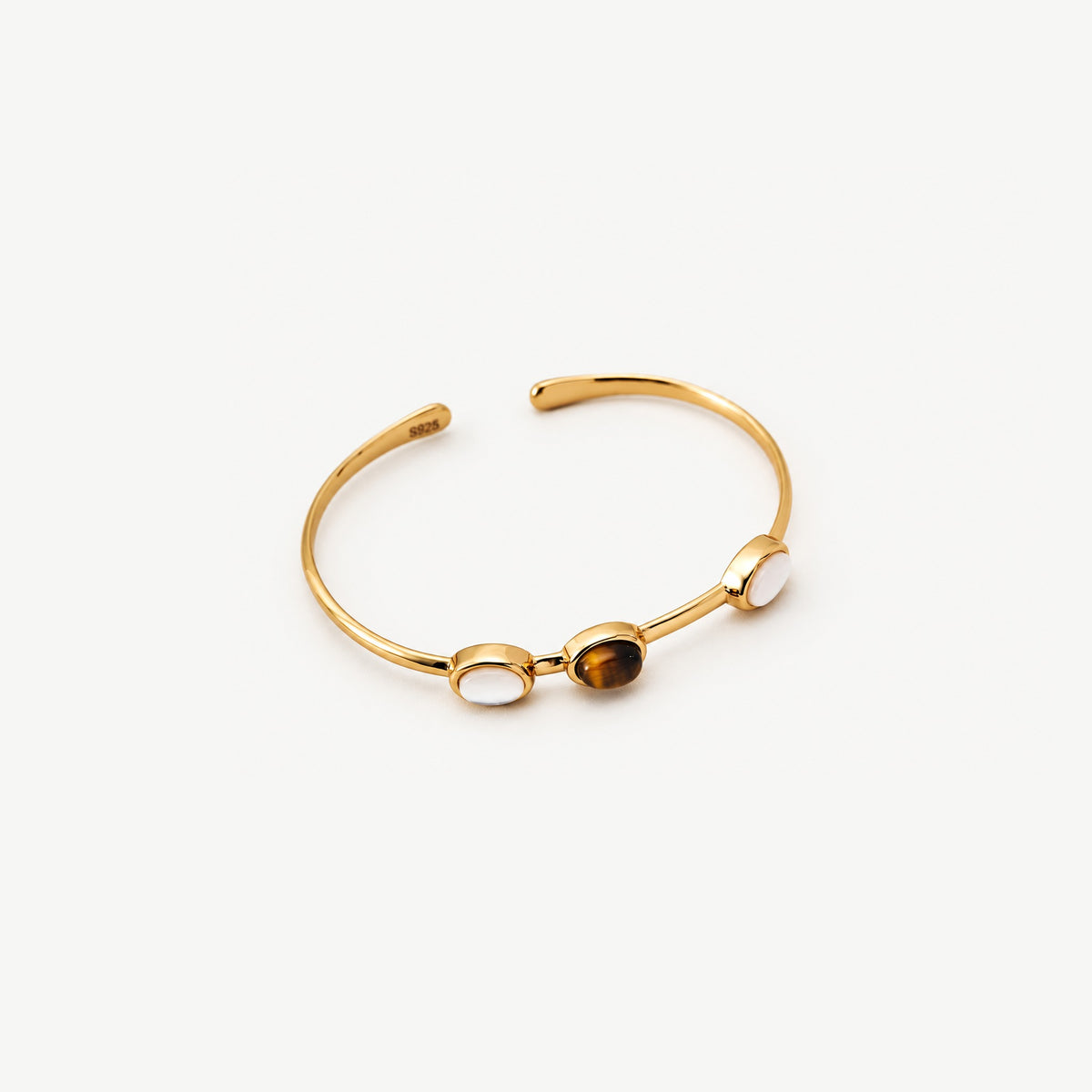 Thin gold-plated sterling silver cuff bracelet from above, a tiger eye stone between two white ovals, open ends